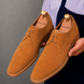 Man holding a pair of Melodiapelle Maringa Suede Chukka Boots in camel suede, close-up