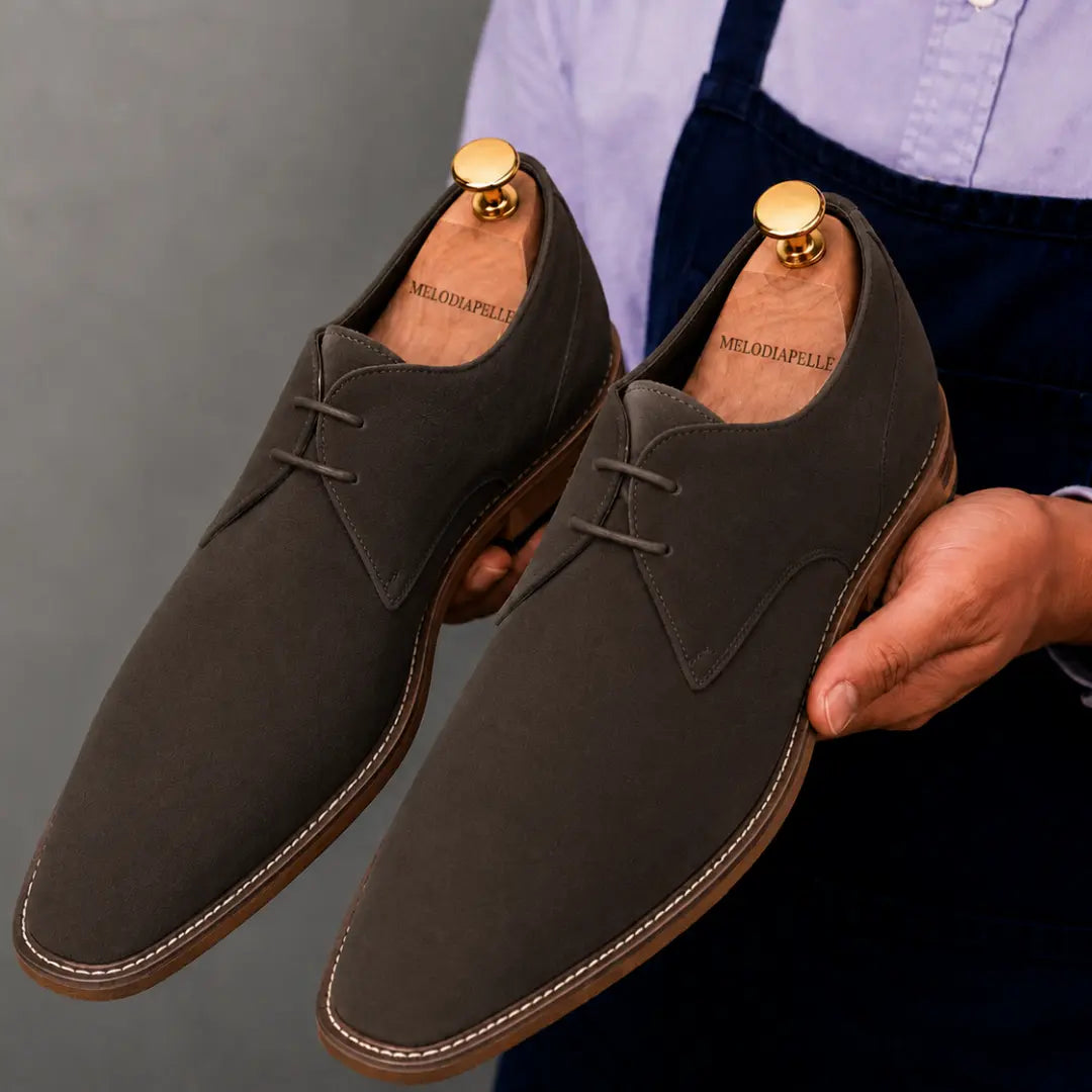 Man holding a pair of Melodiapelle Maringa Suede Chukka Boots in dark brown suede, close-up
