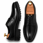 Black leather plain-toe Derby, three-quarter angle showing heel and sole detailing