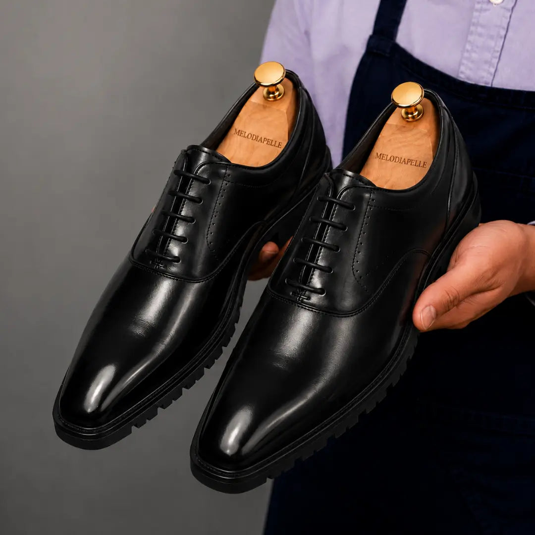 Man holding a pair of Melodiapelle Marlboro Derby Shoes in black leather, close-up