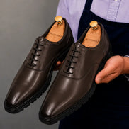 Man holding a pair of Melodiapelle Marlboro Derby Shoes in dark brown leather, close-up