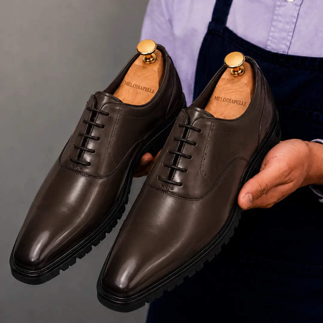 Man holding a pair of Melodiapelle Marlboro Derby Shoes in dark brown leather, close-up