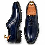 Navy blue leather plain-toe Derby, three-quarter angle showing heel and sole detailing