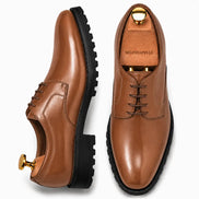Tan leather plain-toe Derby, three-quarter angle showing heel and sole detailing