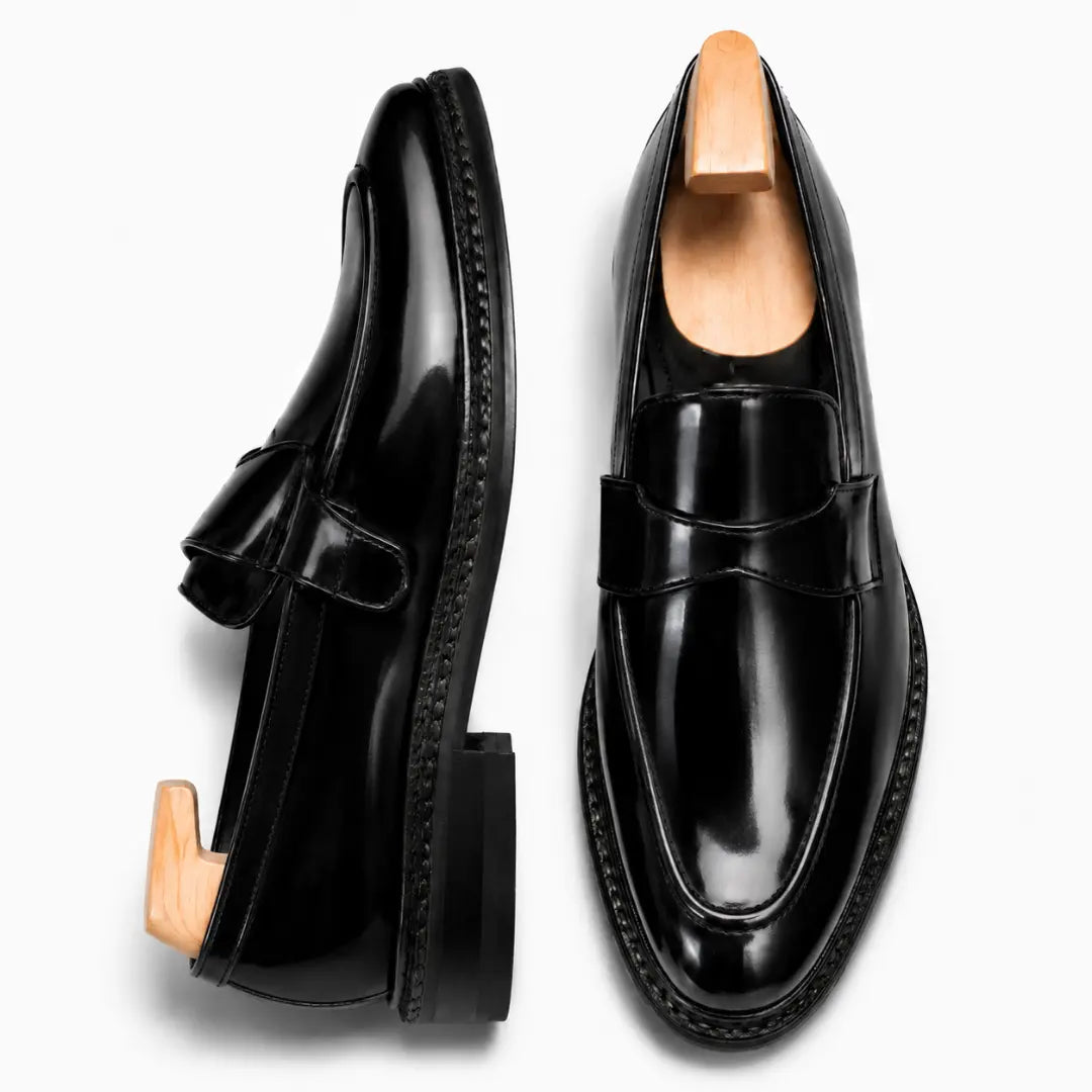 Black leather dress penny loafer, three-quarter angle showing heel and penny strap