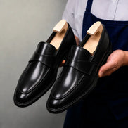 Man holding a pair of Melodiapelle Marquis Dress Penny Loafer shoes in black leather, close-up