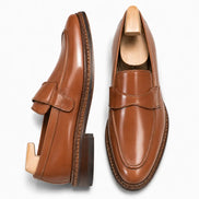 Tan leather dress penny loafer, three-quarter angle showing heel and penny strap
