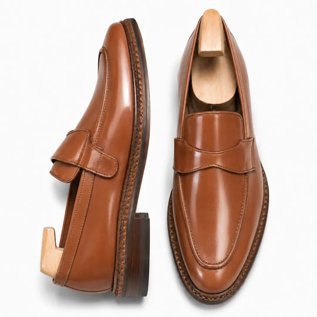 Tan leather dress penny loafer, three-quarter angle showing heel and penny strap