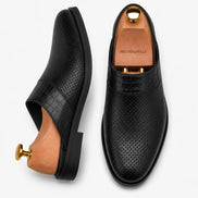 Black perforated leather mule, three-quarter angle showing buckle and sole detailing