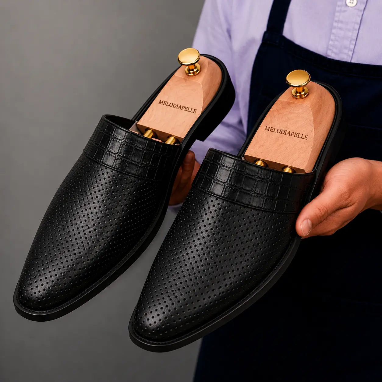 Man holding a pair of Melodiapelle Marshall Mules in black leather, close-up