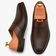 Dark brown perforated leather mule, three-quarter angle showing buckle and sole detailing
