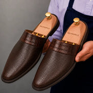 Man holding a pair of Melodiapelle Marshall Mules in dark brown leather, close-up