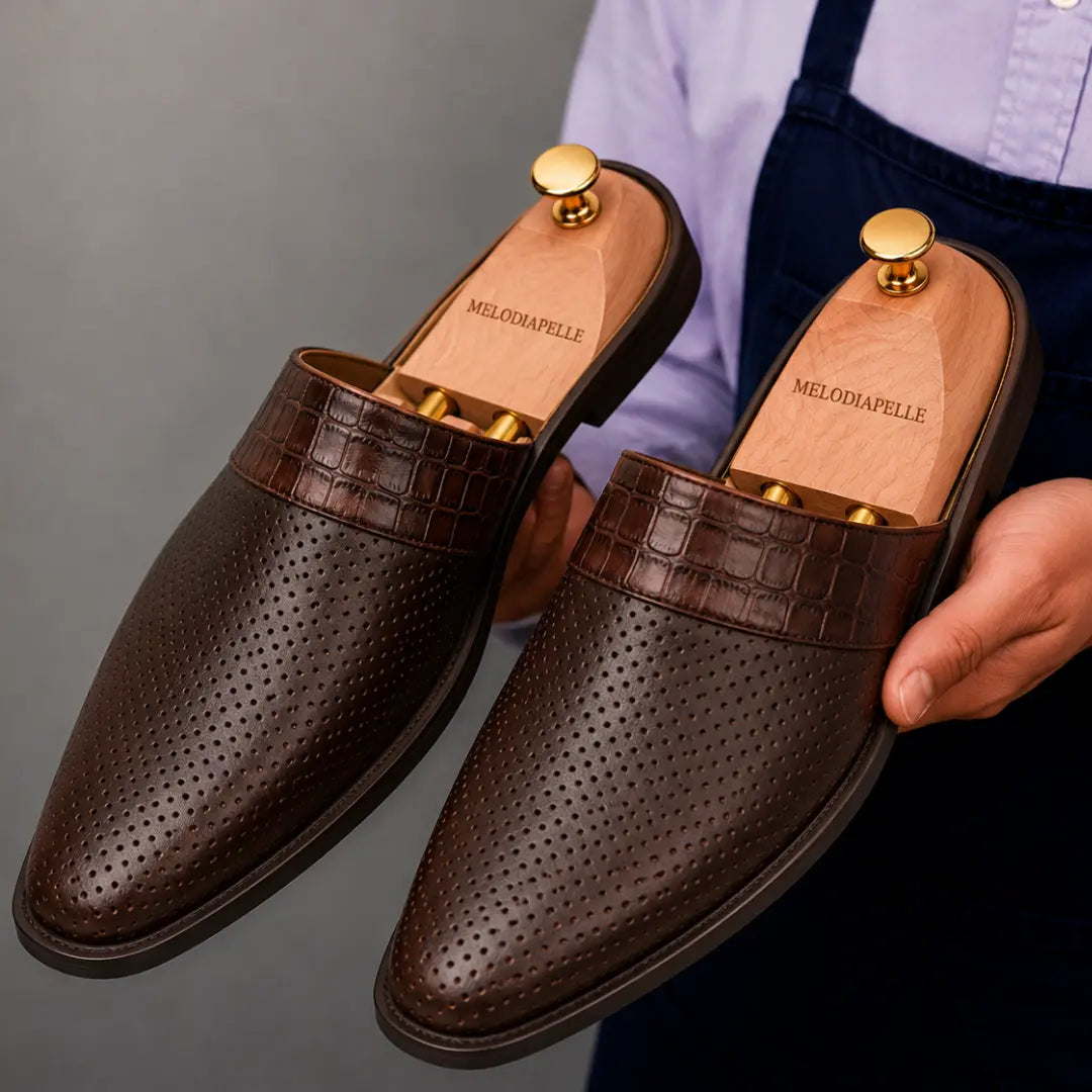 Man holding a pair of Melodiapelle Marshall Mules in dark brown leather, close-up