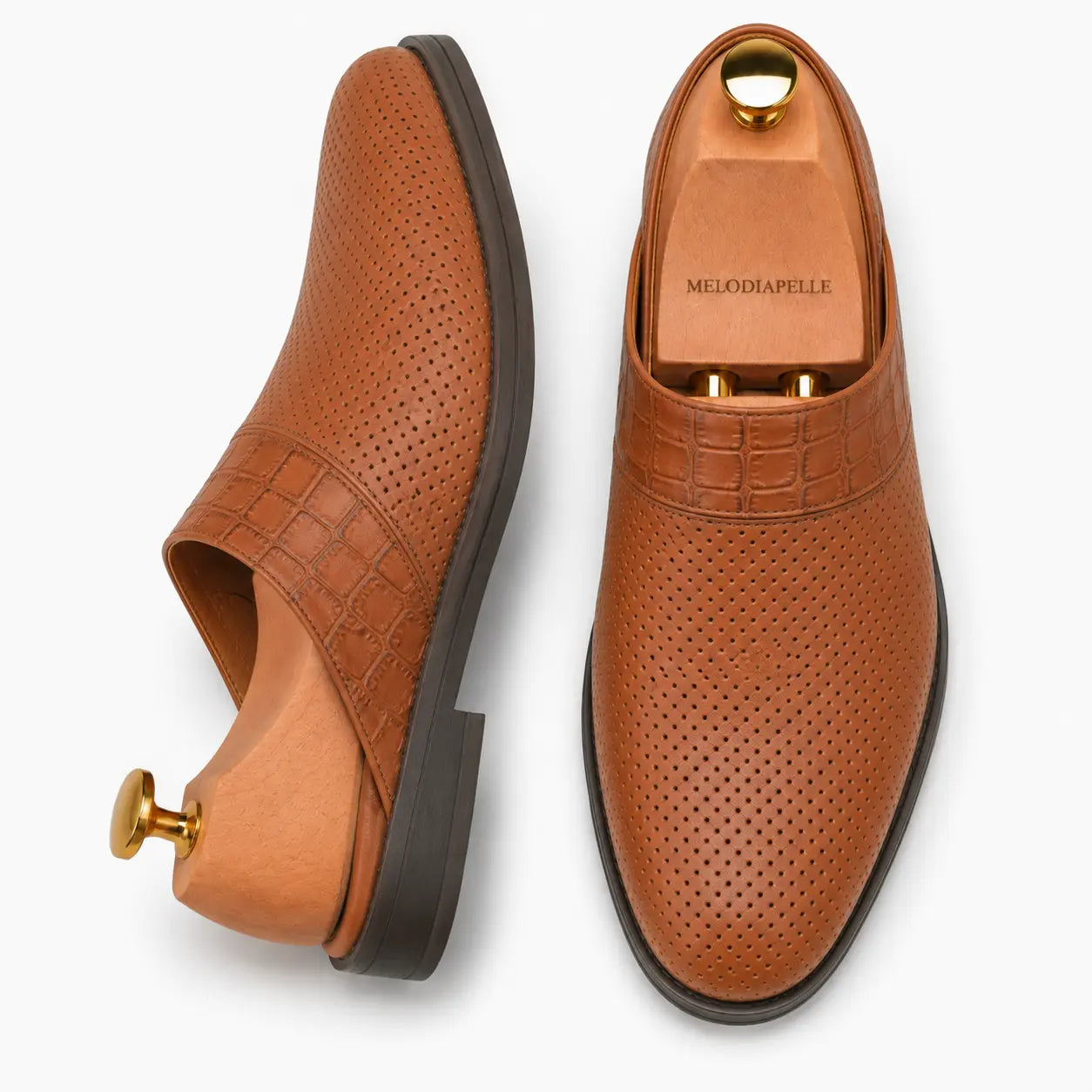 Tan perforated leather mule, three-quarter angle showing buckle and sole detailing