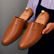 Man holding a pair of Melodiapelle Marshall Mules in tan leather, close-up