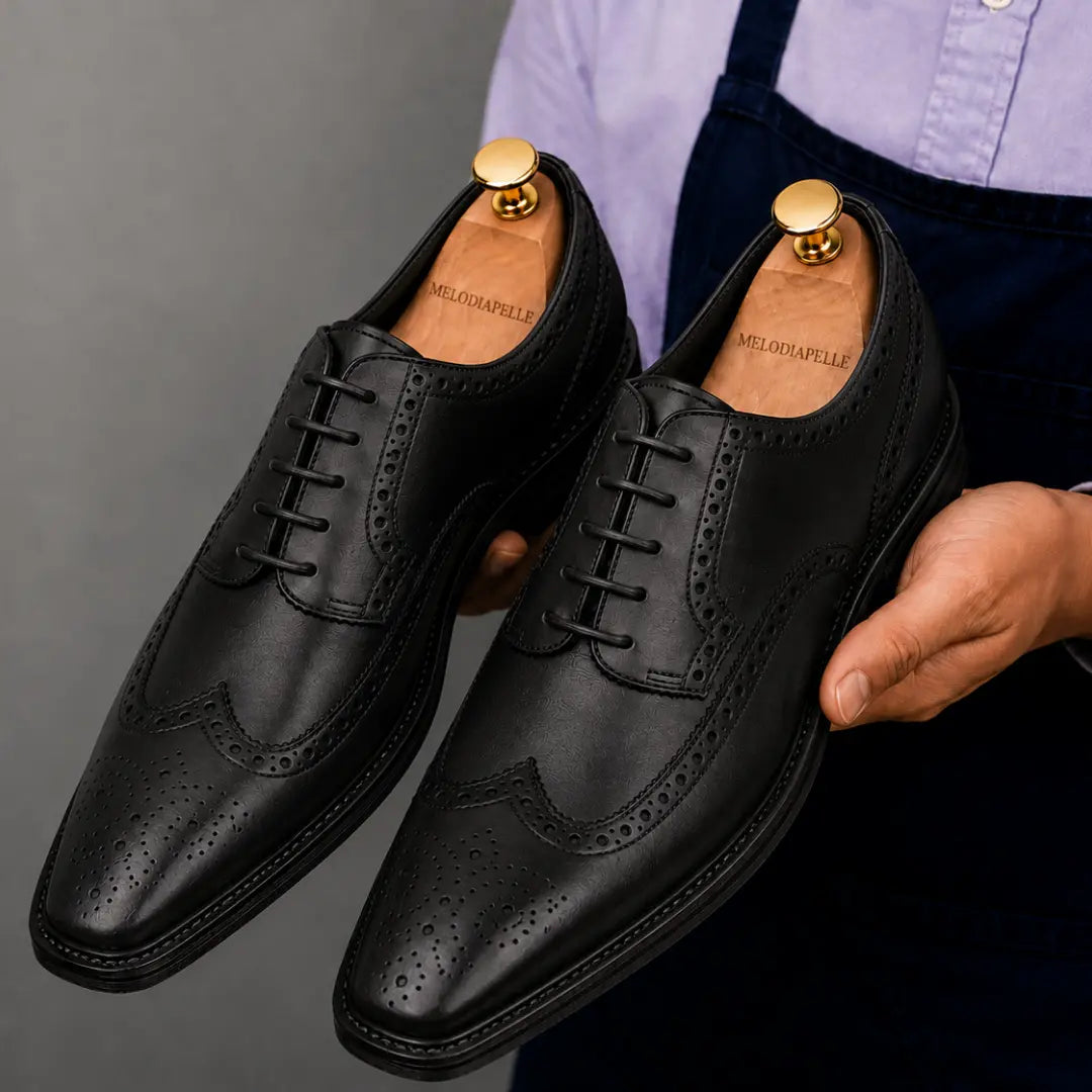 Man holding a pair of Melodiapelle Marshfield Wingtip Brogue Oxford shoes in black leather, close-up