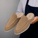 Man holding a pair of Melodiapelle Martia Mule shoes in sand beige suede, close-up
