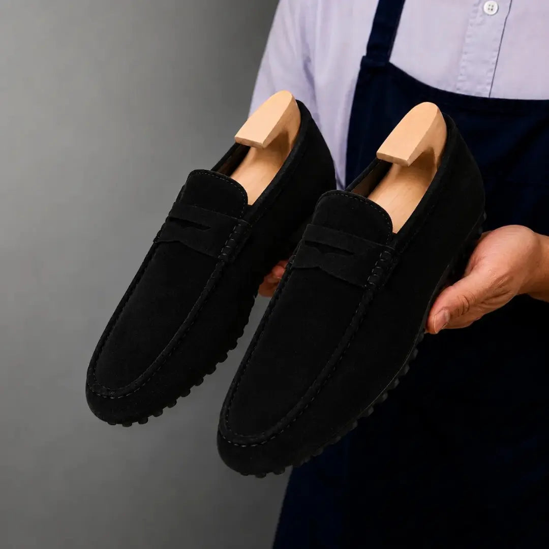 Man holding a pair of Melodiapelle Maryland Loafers in black suede, close-up