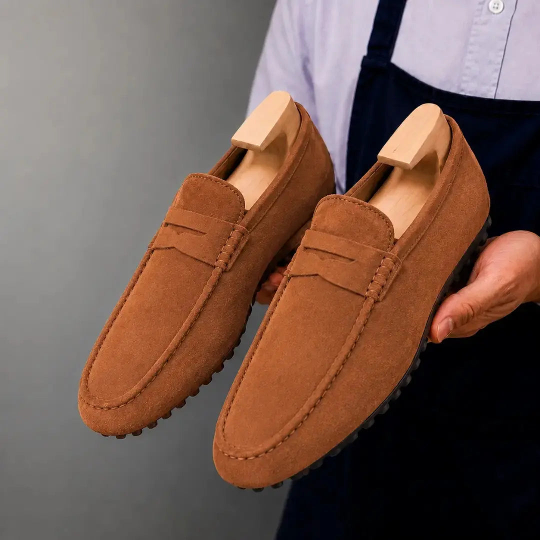 Man holding a pair of Melodiapelle Maryland Loafers in rust tan suede, close-up