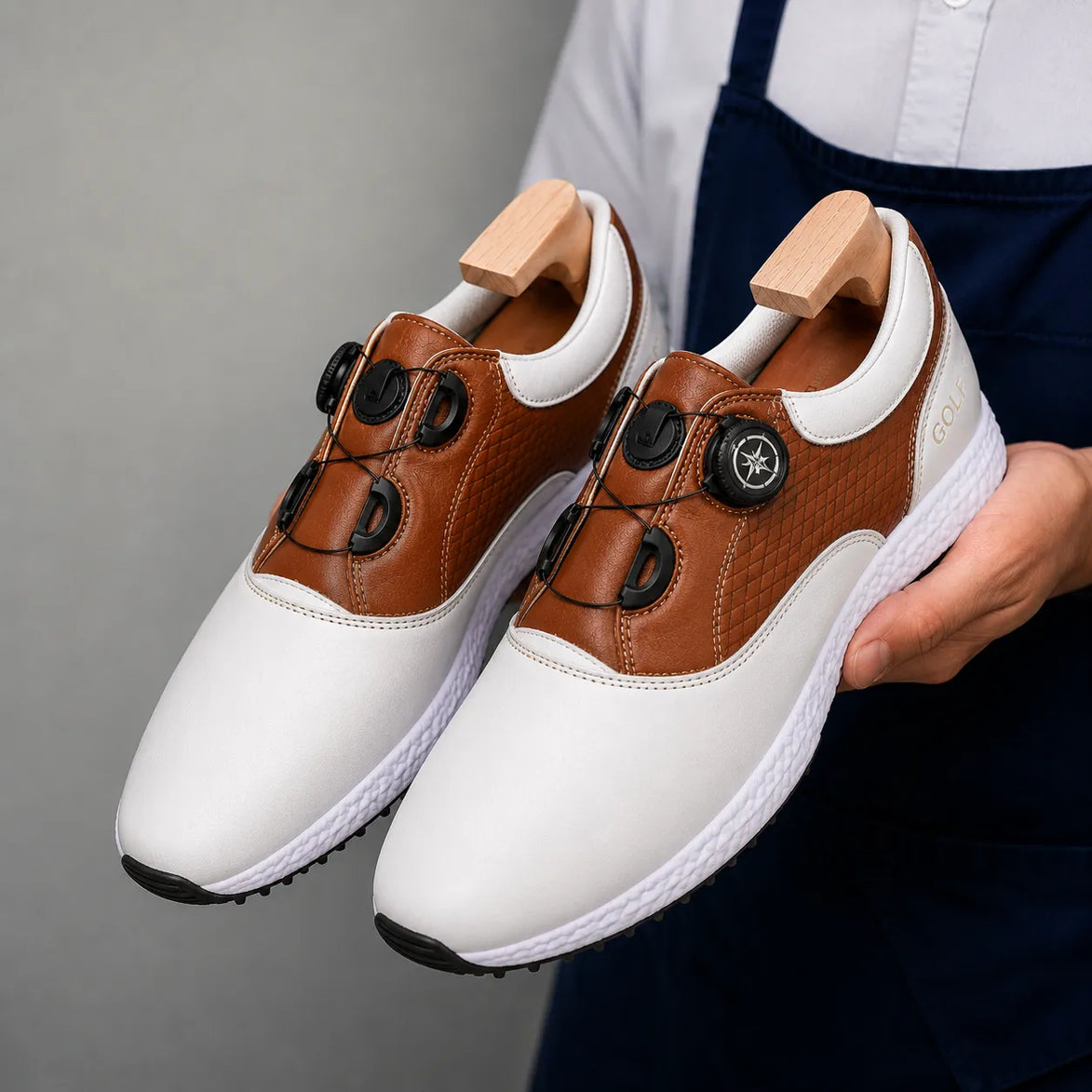 Man holding a pair of Melodiapelle Marzano BOA Golf Shoes in white and tan leather, close-up