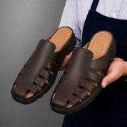 Man holding a pair of Melodiapelle Mason Mules in dark brown leather, close-up