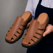 Man holding a pair of Melodiapelle Mason Mules in tan leather, close-up