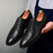Man holding a pair of Melodiapelle Matador Apron-Toe Derby shoes in nero black leather, close-up