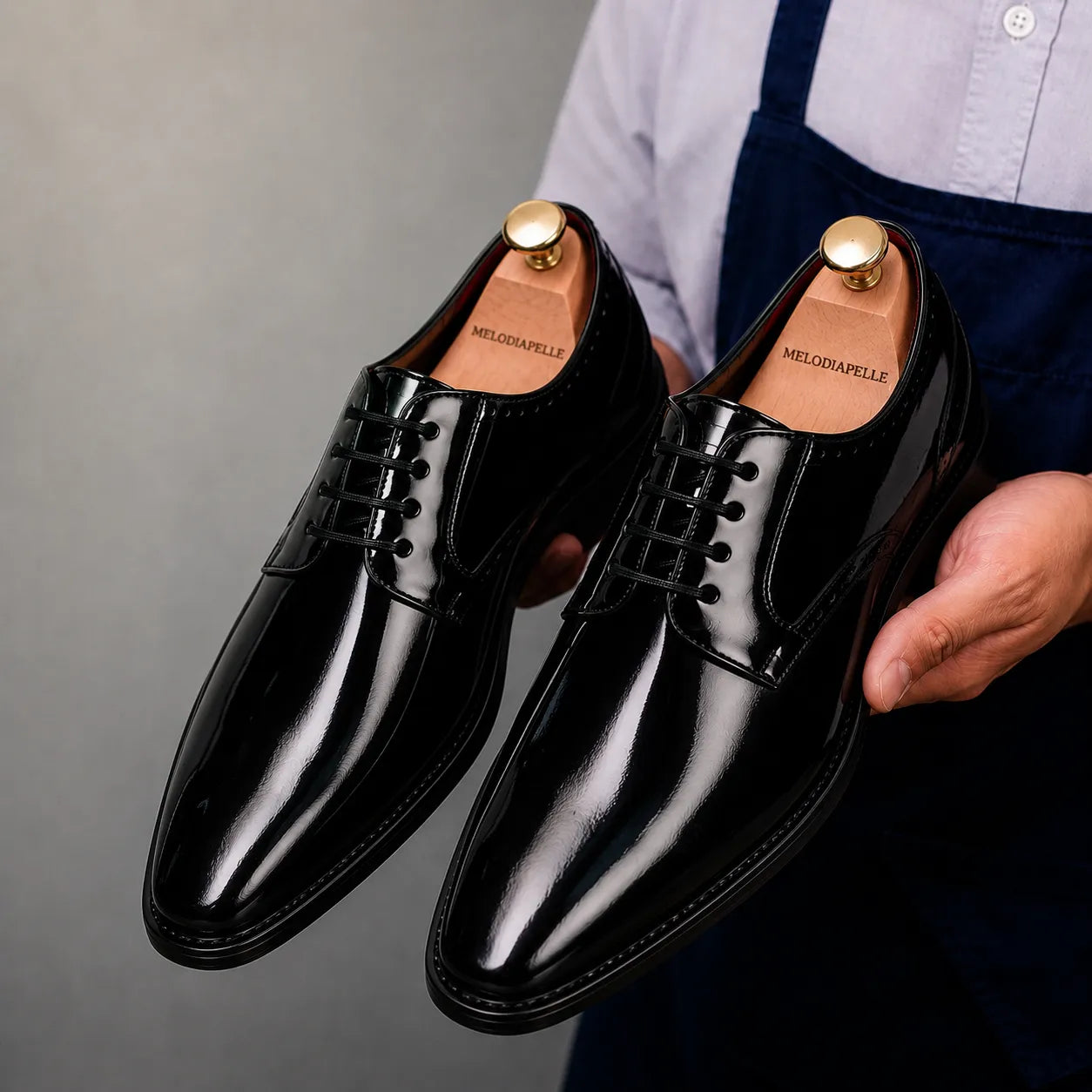 Man holding a pair of Melodiapelle Matera Plain-Toe Derby shoes in nero black leather, close-up