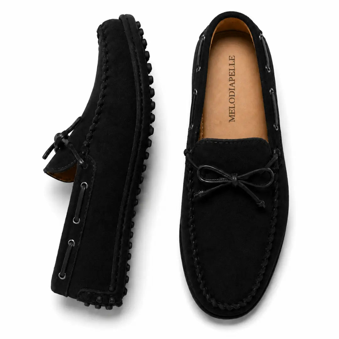 Black suede driving loafer with bow lace, three-quarter angle showing sole detailing