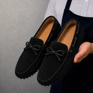 Man holding a pair of Melodiapelle Mathews Loafers in black suede, close-up