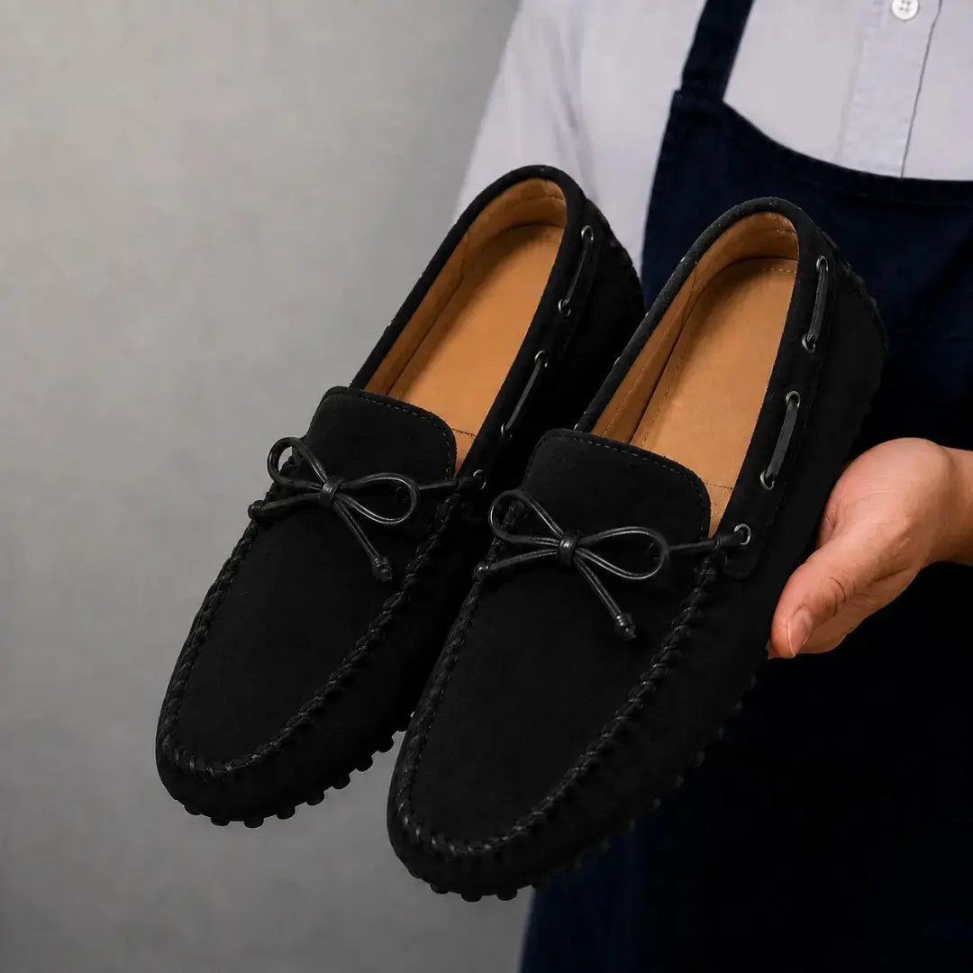 Man holding a pair of Melodiapelle Mathews Loafers in black suede, close-up