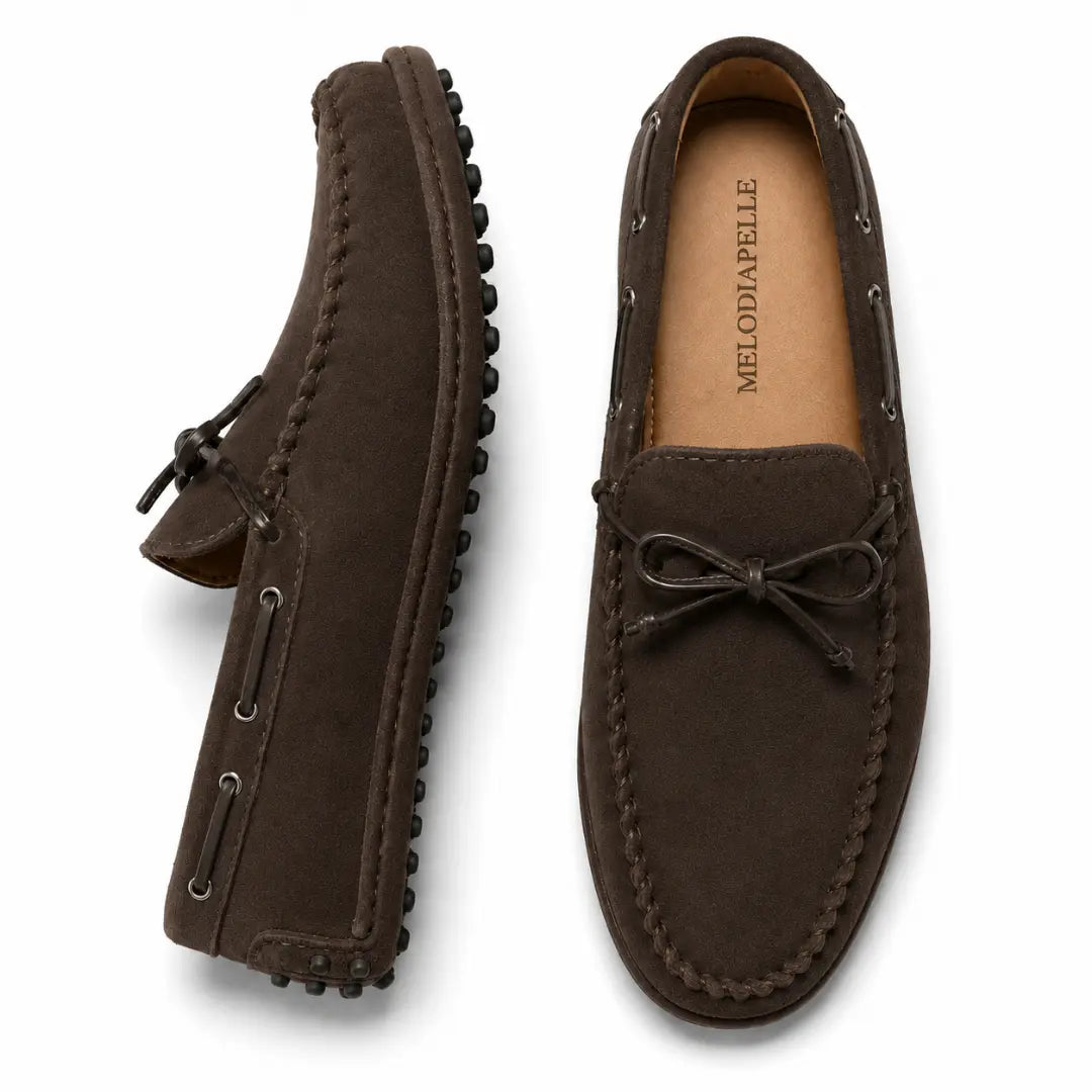Dark brown suede driving loafer with bow lace, three-quarter angle showing sole detailing