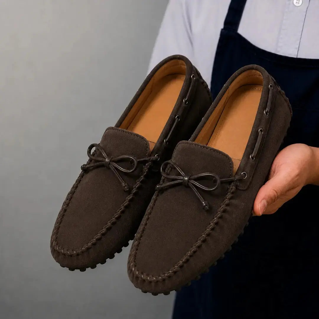 Man holding a pair of Melodiapelle Mathews Loafers in dark brown suede, close-up