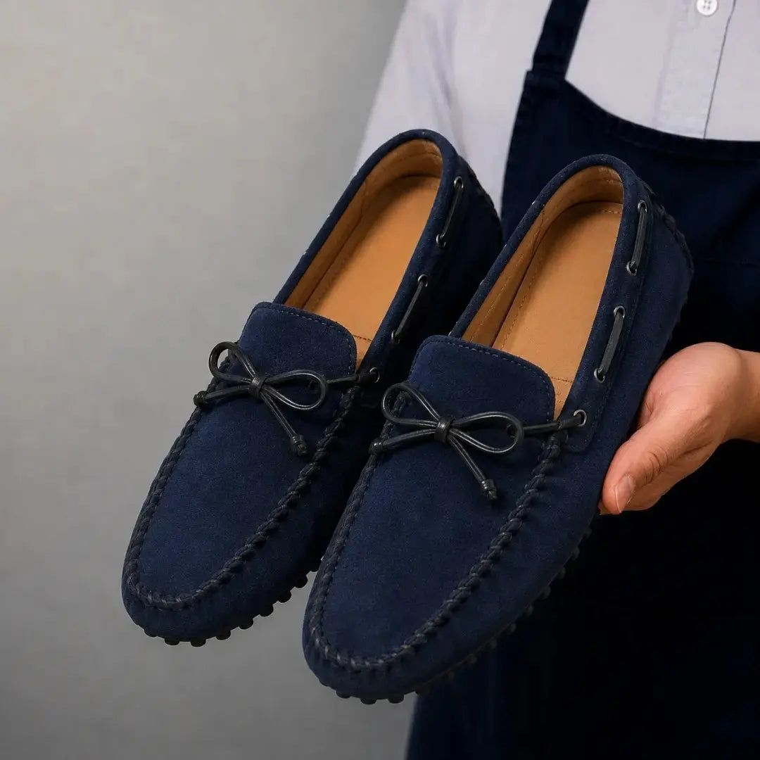 Man holding a pair of Melodiapelle Mathews Loafers in navy blue suede, close-up