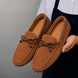 Man holding a pair of Melodiapelle Mathews Loafers in rust tan suede, close-up