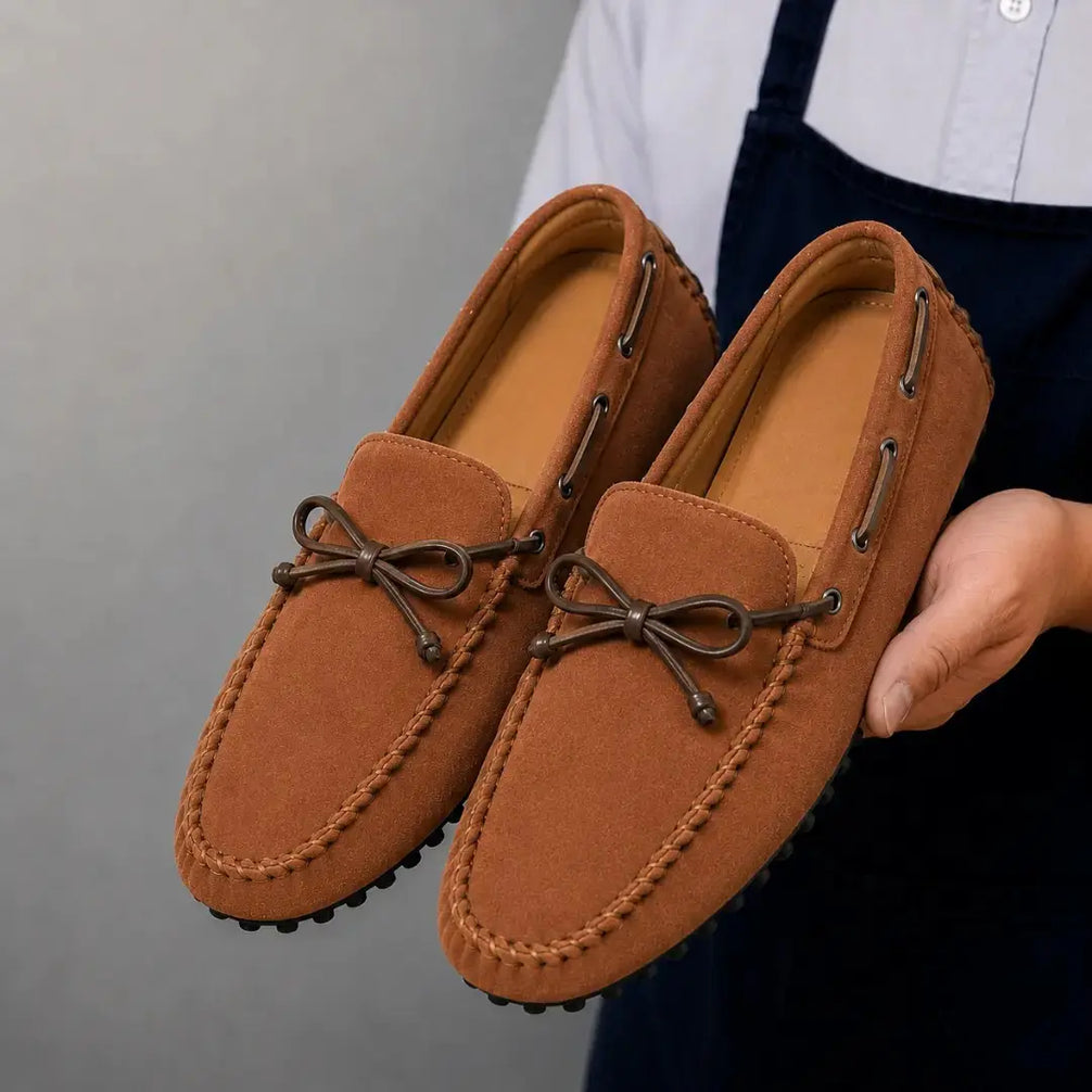 Man holding a pair of Melodiapelle Mathews Loafers in rust tan suede, close-up