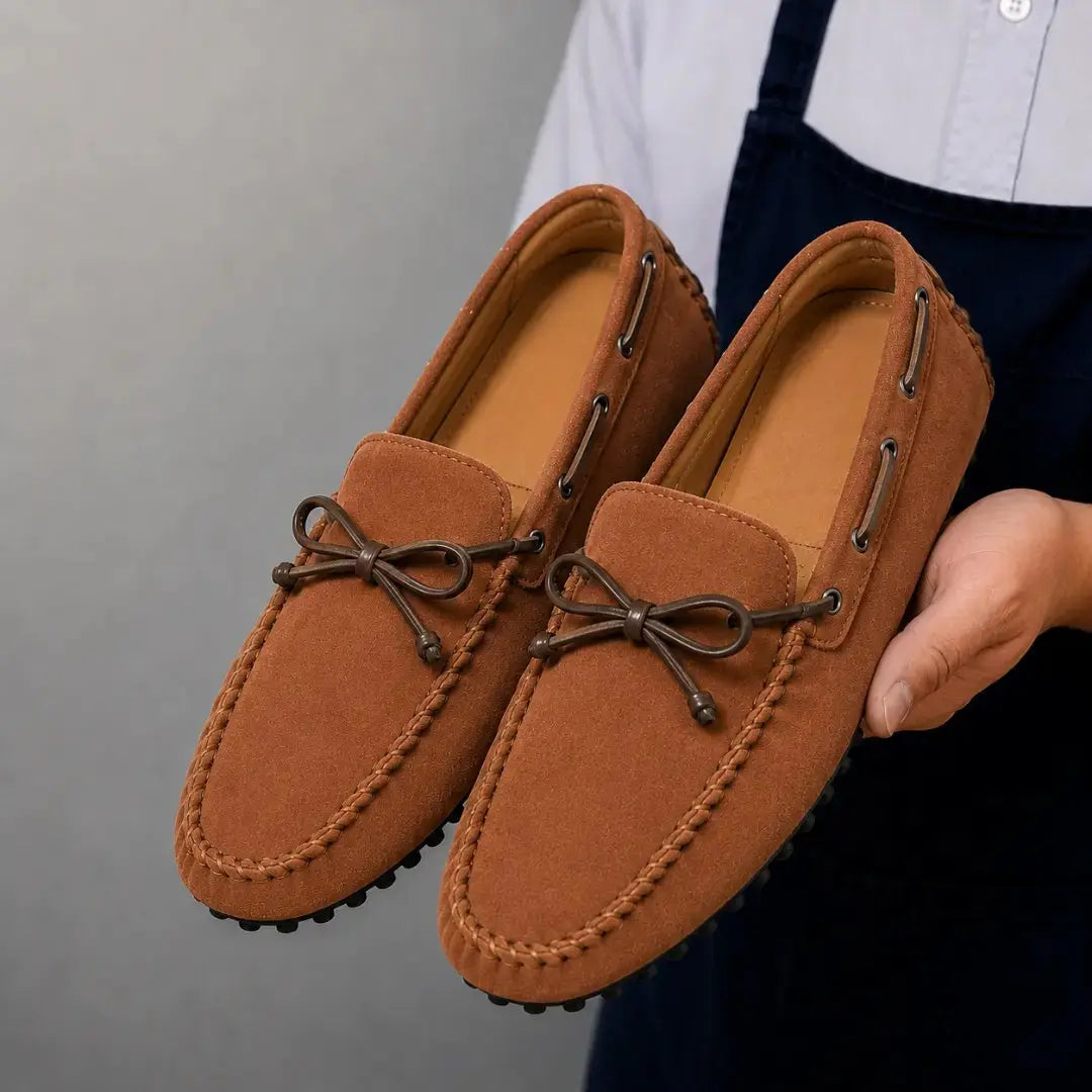 Man holding a pair of Melodiapelle Mathews Loafers in rust tan suede, close-up