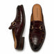 Oxblood brown croc-embossed leather horsebit mule, three-quarter angle showing buckle and heel