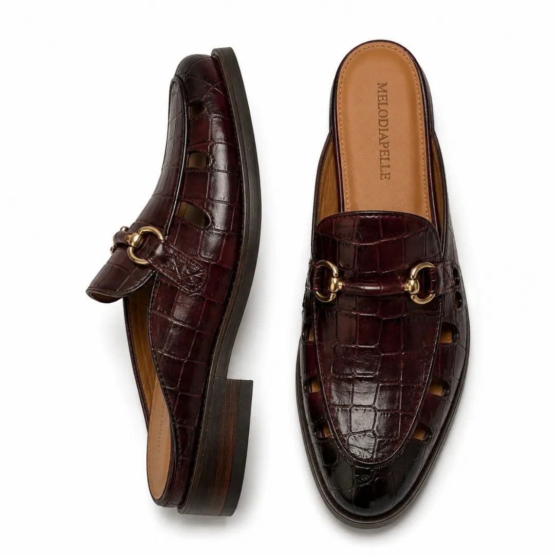 Oxblood brown croc-embossed leather horsebit mule, three-quarter angle showing buckle and heel