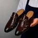 Man holding a pair of Melodiapelle Matilda Mule shoes in oxblood brown croc-embossed leather, close-up