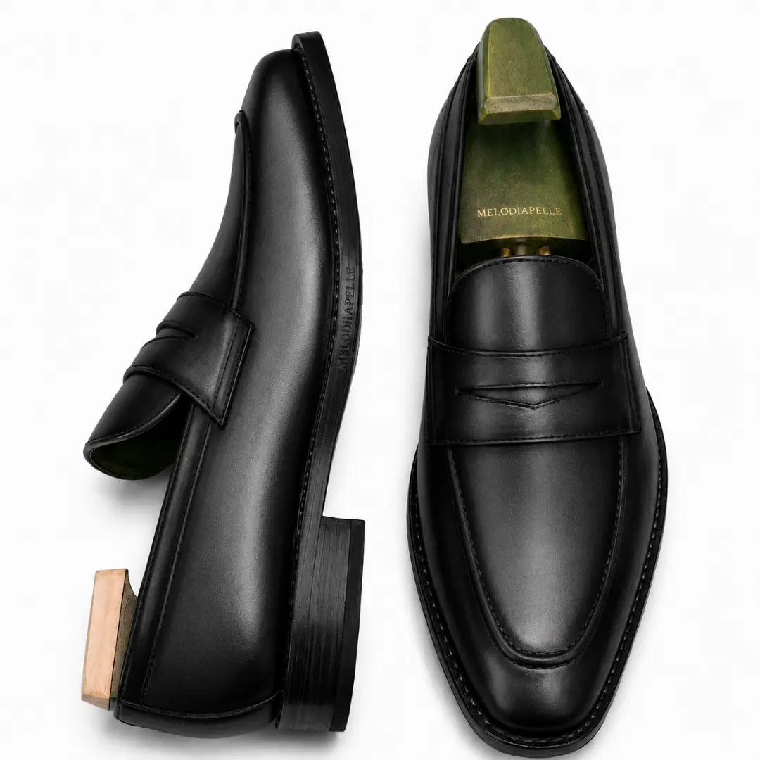 Black leather penny loafer, three-quarter angle showing heel and penny strap