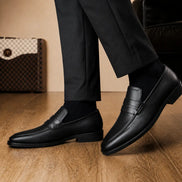 Man holding a pair of Melodiapelle Maximus Dress Penny Loafer shoes in black leather, close-up