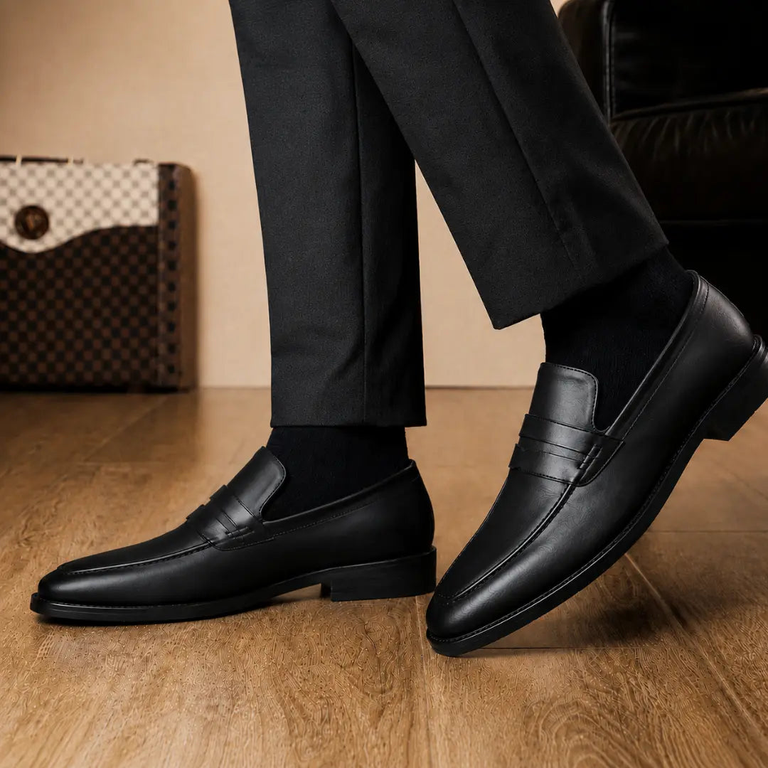 Man holding a pair of Melodiapelle Maximus Dress Penny Loafer shoes in black leather, close-up