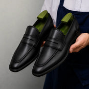 Side profile of the Maximus Dress Penny Loafer in black leather on white background
