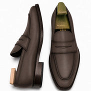 Brown leather penny loafer, three-quarter angle showing heel and penny strap