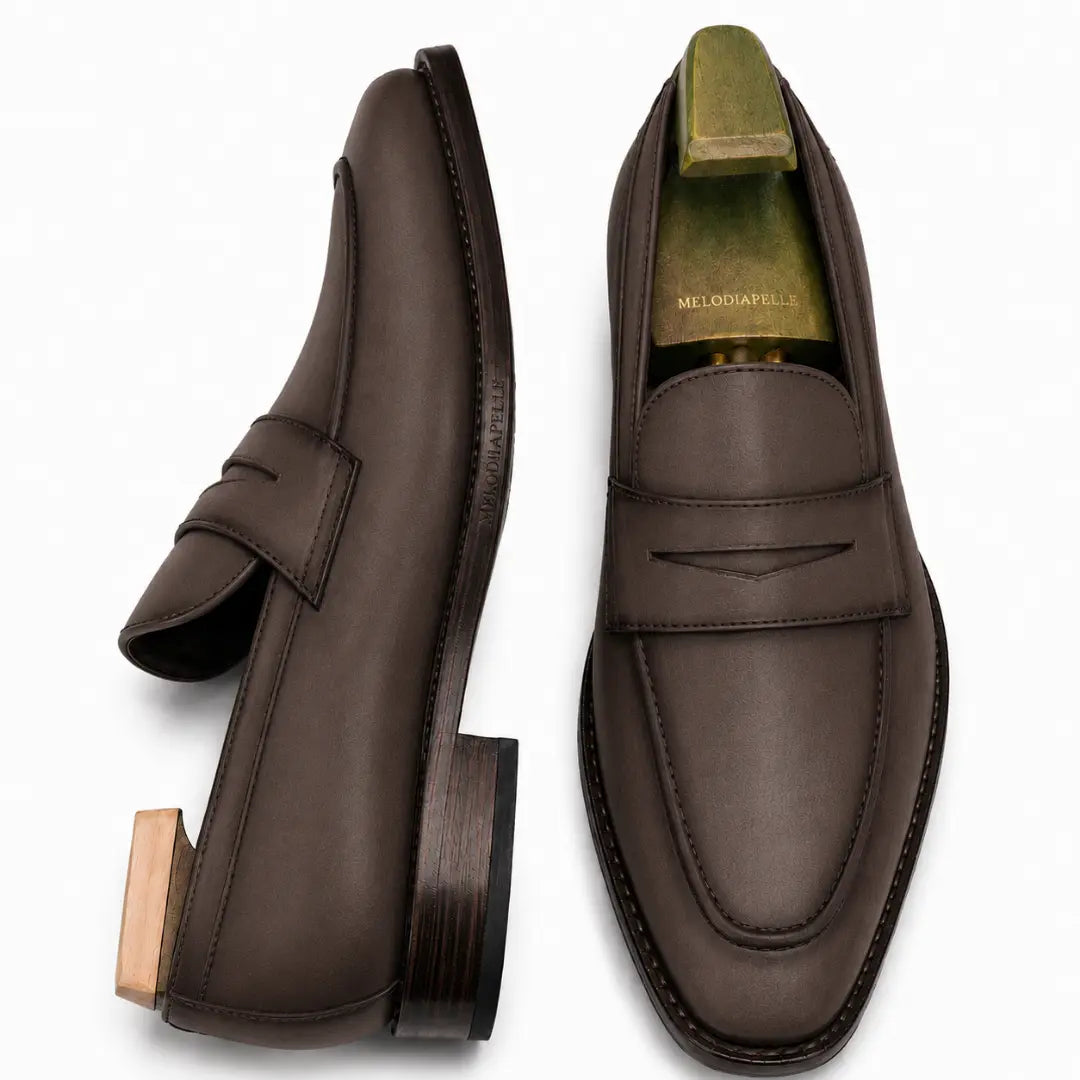 Brown leather penny loafer, three-quarter angle showing heel and penny strap