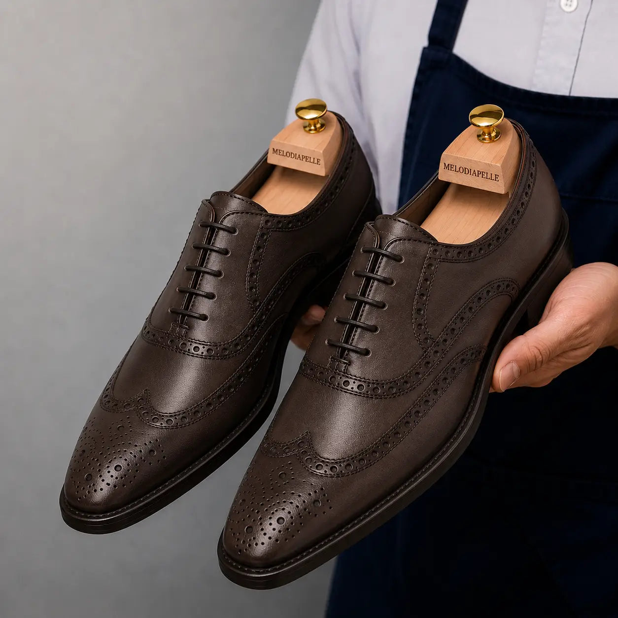 Man holding a pair of Melodiapelle Mazaro Wingtip Brogue Oxford shoes in dark brown leather, close-up