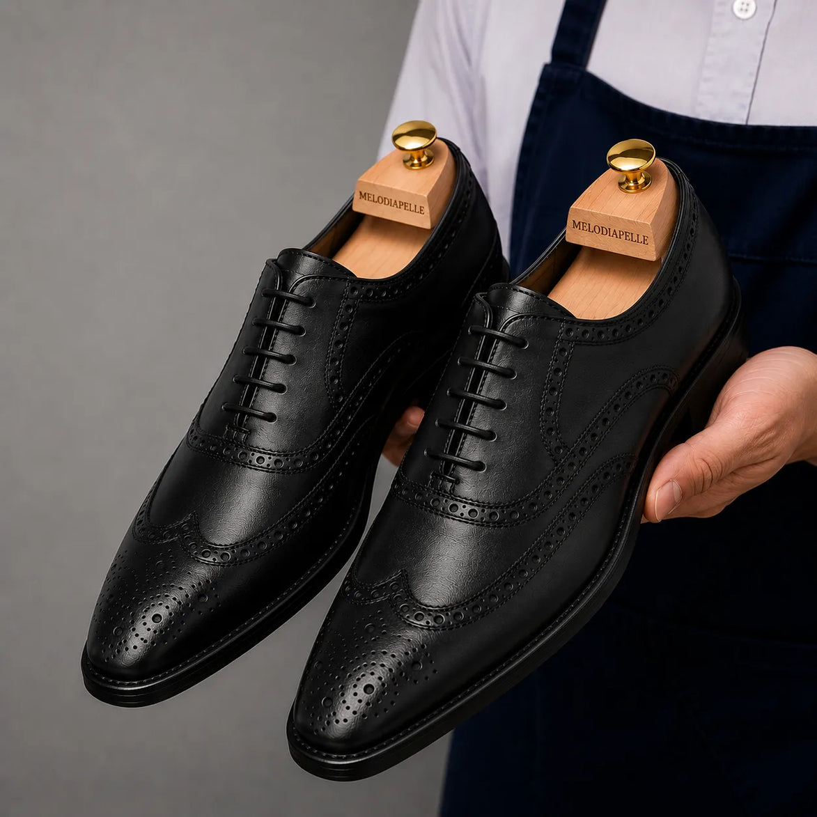 Man holding a pair of Melodiapelle Mazaro Wingtip Brogue Oxford shoes in nero black leather, close-up