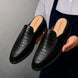 Man holding a pair of Melodiapelle Mckinsey Mule shoes in black croc-embossed leather, close-up