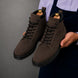 Man holding a pair of Melodiapelle Meilbourne Combat Boots in dark brown suede, close-up